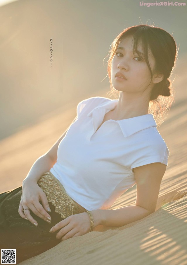 A woman sitting on top of a sand dune in the desert.