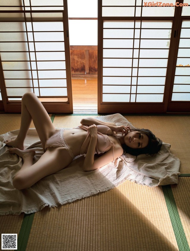 A woman laying on a bed in front of a window.