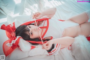 A woman in a red and white outfit sitting on a bed.