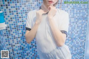A woman in a white shirt and blue shorts posing in a bathtub.
