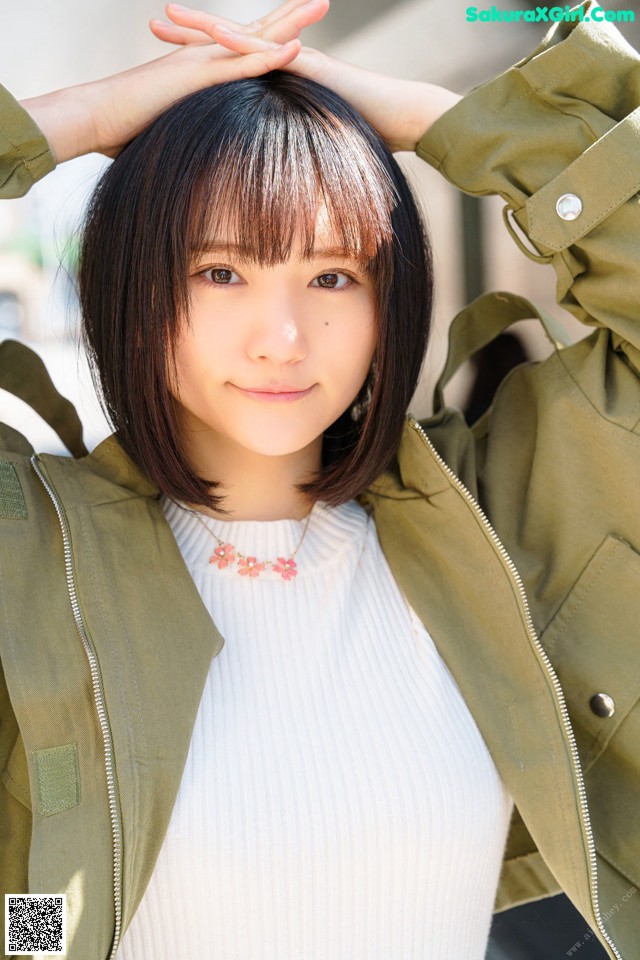 A woman wearing a green jacket and a white top.