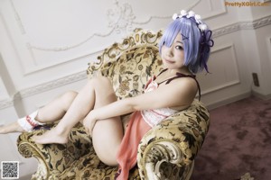 A woman with blue hair sitting on a bed.