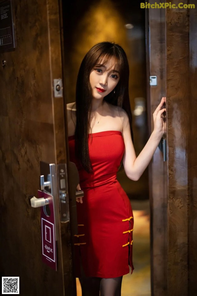 A woman in a red dress standing in an elevator.