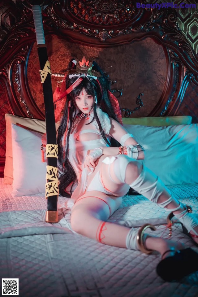 A woman sitting on a bed holding a sword.