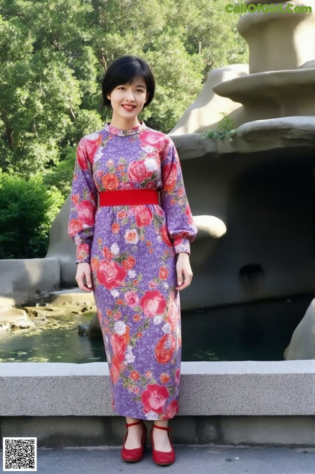 A woman in a purple dress standing in front of a fountain.