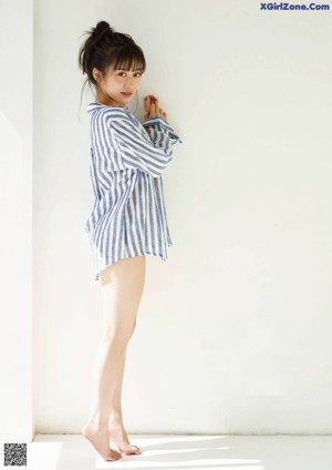 A woman in a blue and white striped shirt is posing for a magazine.