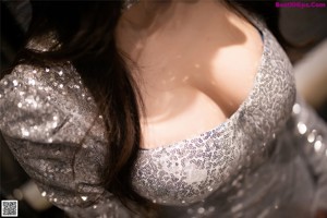 A woman in a silver dress sitting on a table.