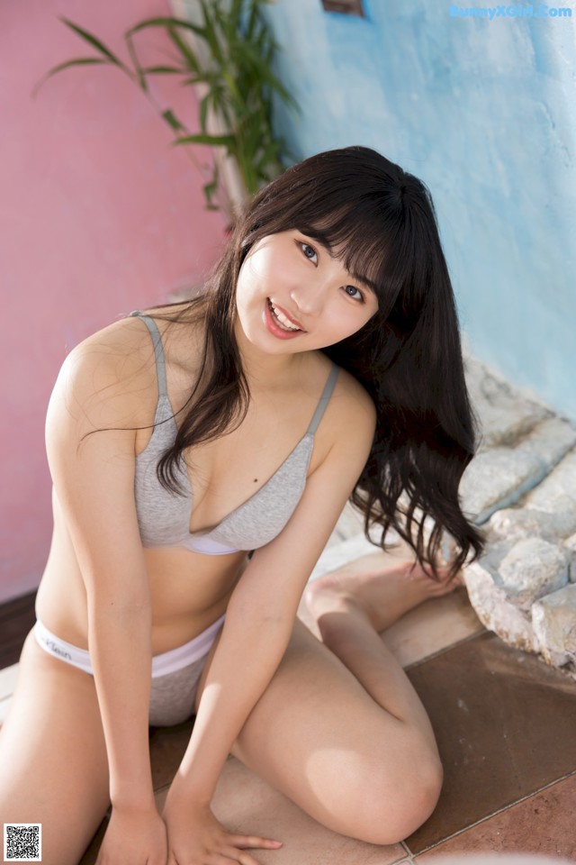 A woman in a gray bikini sitting on the ground.