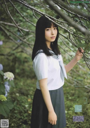 A woman in a gray dress standing in a field of flowers.