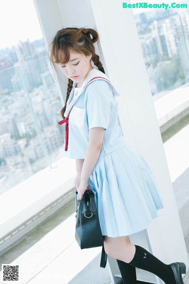 A woman in a blue dress is holding a black bag.