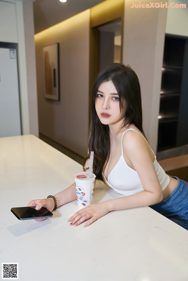 A woman sitting at a table with a cup of coffee and a cell phone.