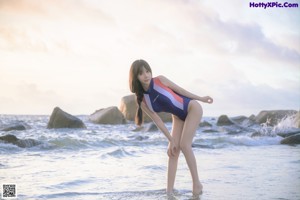 A woman in a bathing suit standing on the beach.