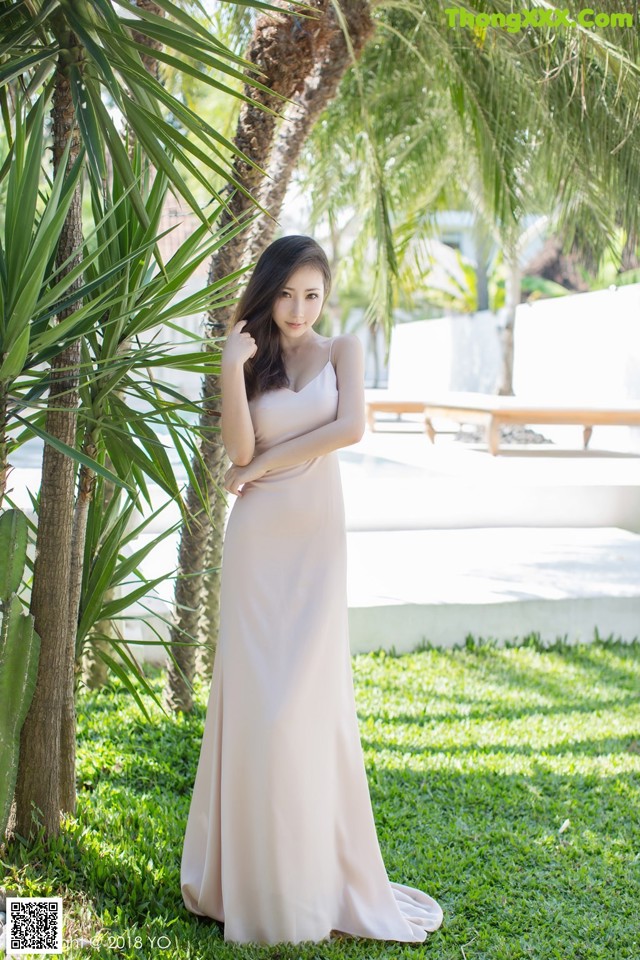 A woman in a long dress standing in the grass.