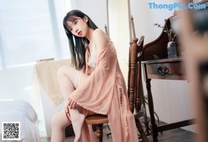 A woman in a white lingerie sitting on a bed.