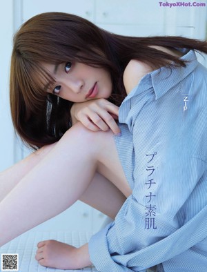 A woman sitting on top of a bed next to a field.
