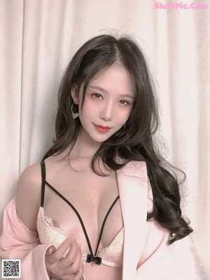 A woman in a pink robe is posing for the camera.
