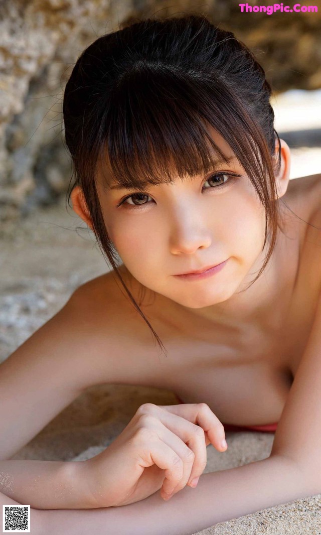 A young woman in a red bikini laying on the sand.