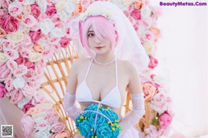 A woman in a pink wig and white lingerie sitting on a bed.