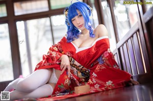 A woman in a red kimono sitting on the floor.