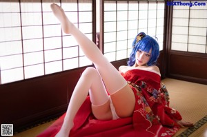A woman in a red kimono sitting on a chair.