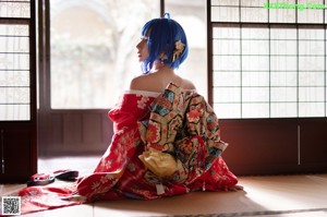 A woman in a red kimono sitting on a bed.