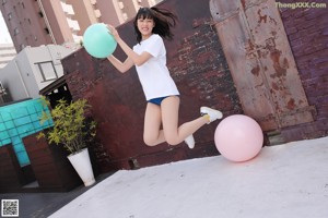 A woman in a white shirt and blue shorts holding a blue ball.