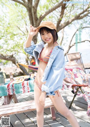 A woman in a blue bikini sitting on a wooden floor.