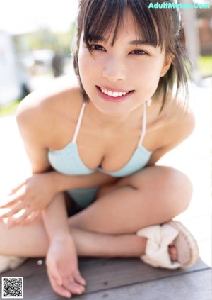 A woman in a bikini and a straw hat posing for a picture.