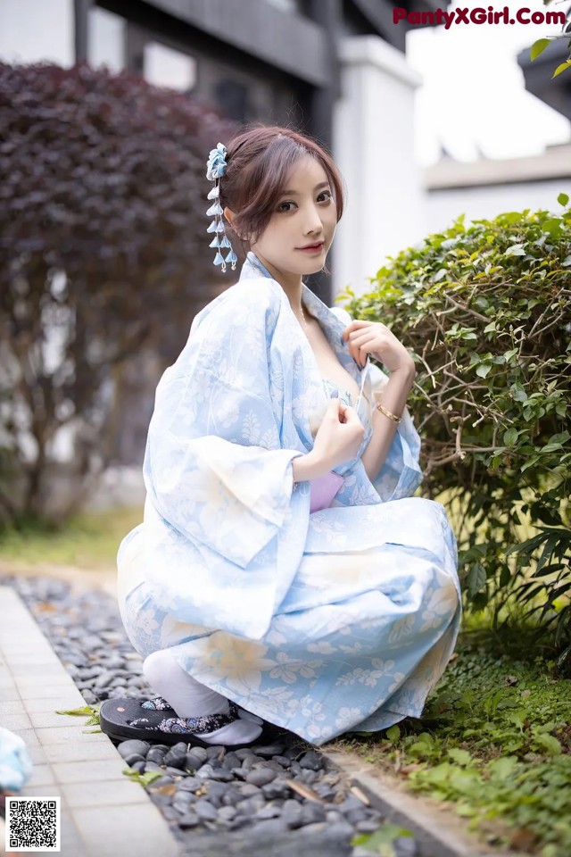 A woman in a blue kimono sitting on the ground.