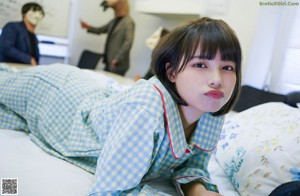 A woman in pajamas stretching on a bed in a classroom.