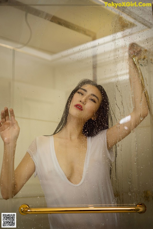 A woman in a white shirt is standing in a shower.