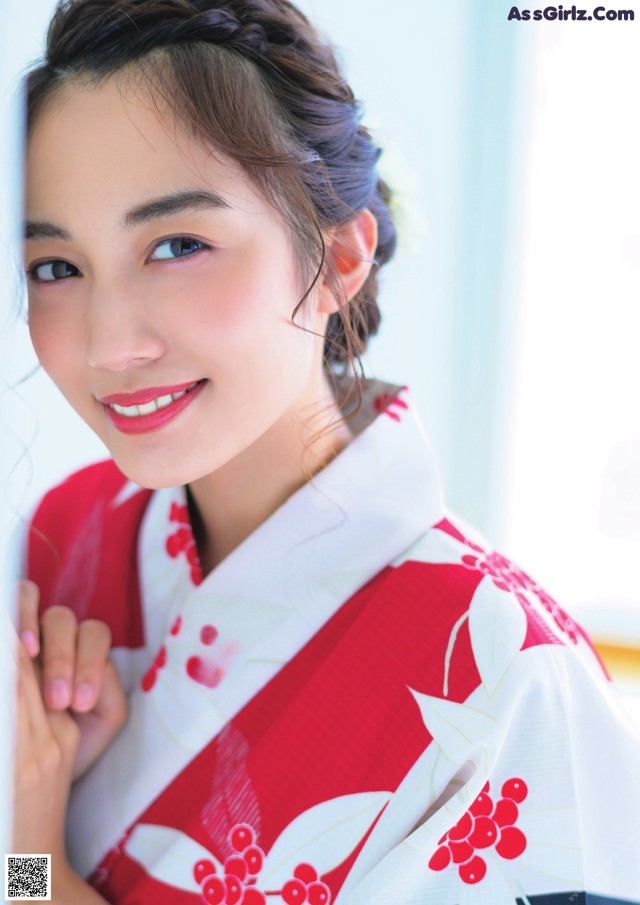 A woman in a red and white kimono leaning against a wall.