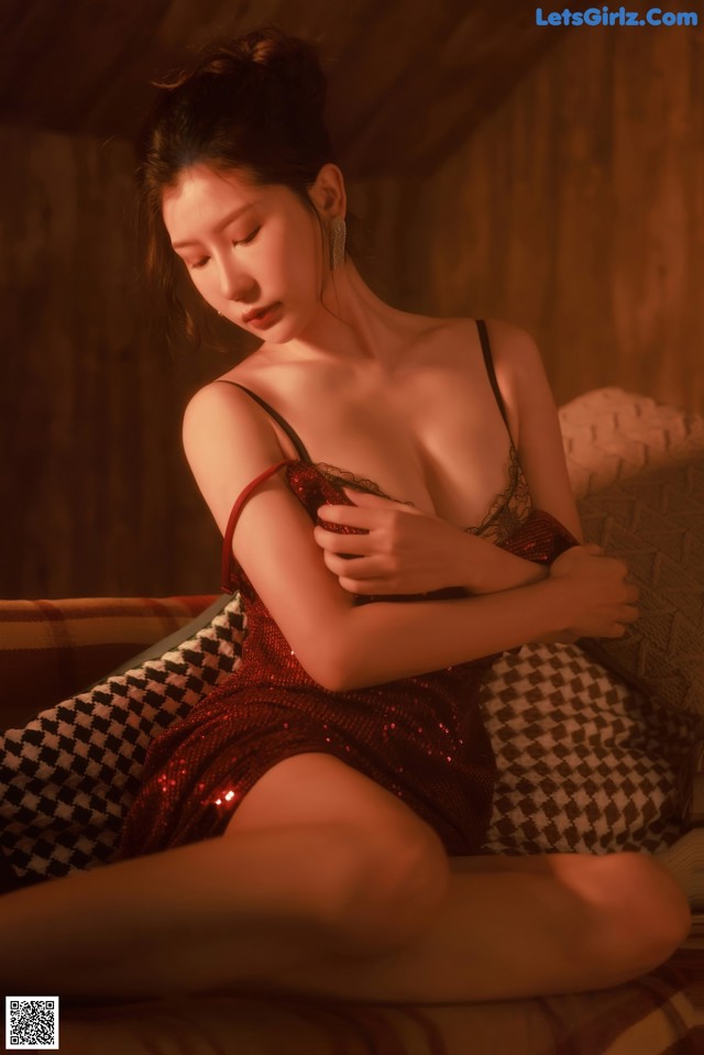 A woman in a red dress sitting on a couch.