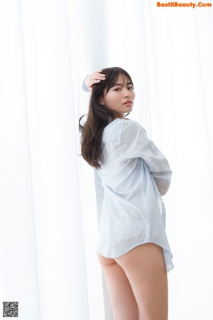 A woman in a white shirt and panties posing for a picture.