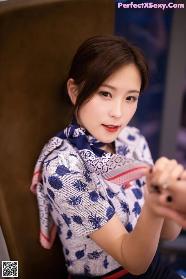 A woman in a blue and white shirt holding a stuffed animal.