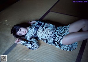 A woman in a kimono sitting on a wooden bench.