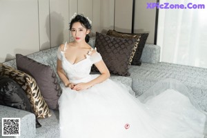 A woman in a wedding dress sitting on a chair.