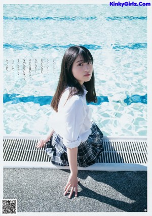 A woman in a blue and black swimsuit standing next to a pool.