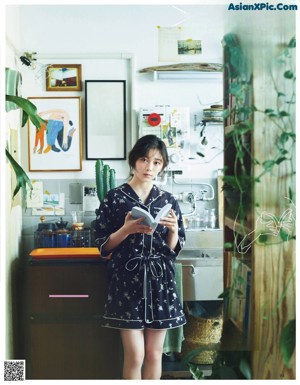 A woman sitting on a chair in a room with plants.