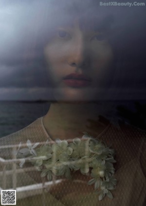 A woman with a flower in her hair looking out of a window.