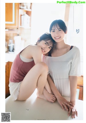 Two young women walking on the beach near the ocean.