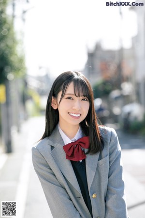 A woman in a school uniform is smiling for the camera.