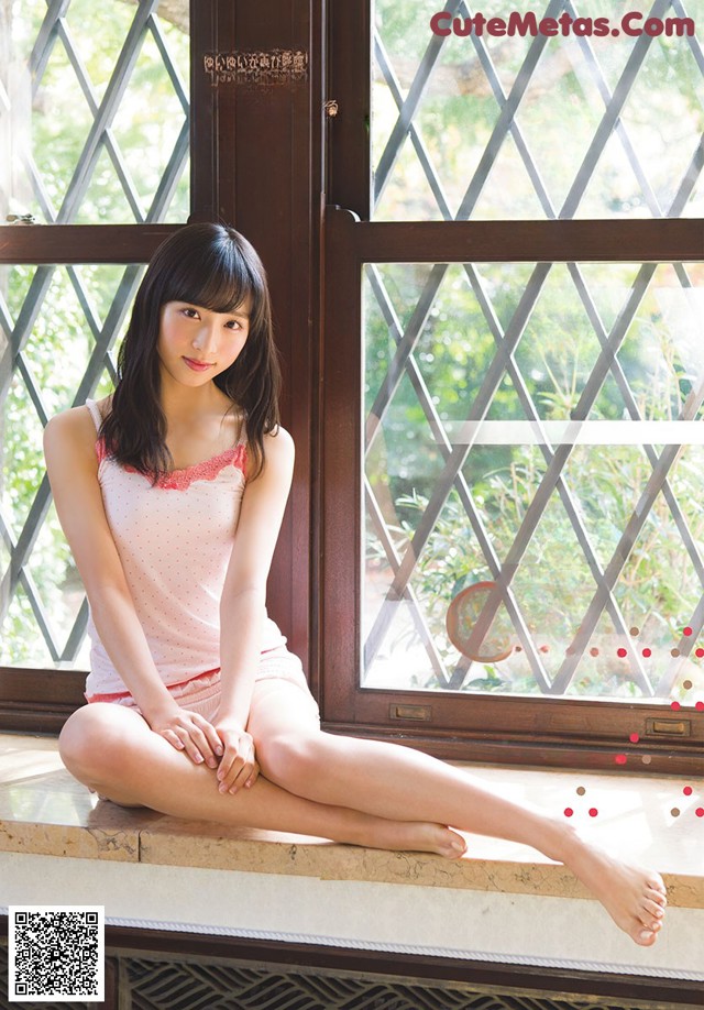 A woman sitting on a window sill in front of a window.