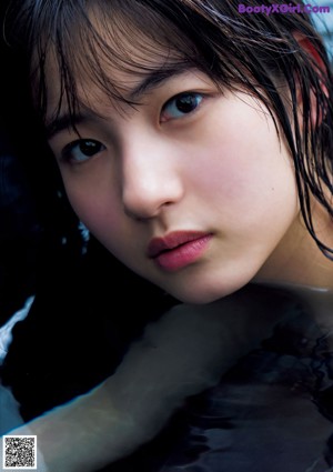 A woman in a black bikini standing in a pool.