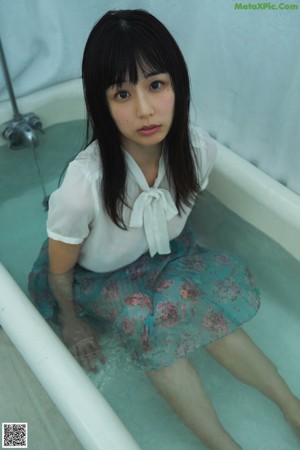 A woman in a pink bikini sitting in a bathtub.