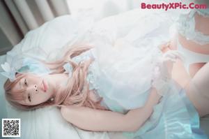 A woman in a white lingerie sitting on a bed.