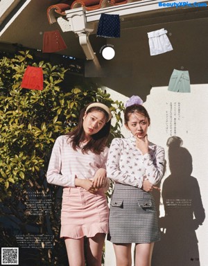 A couple of women sitting next to each other on a wooden floor.