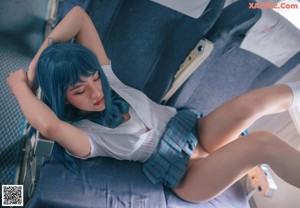 A woman with blue hair sitting on an airplane.