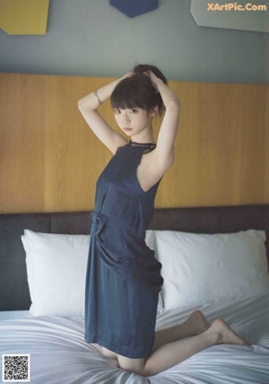 A woman with long black hair laying on a bed.